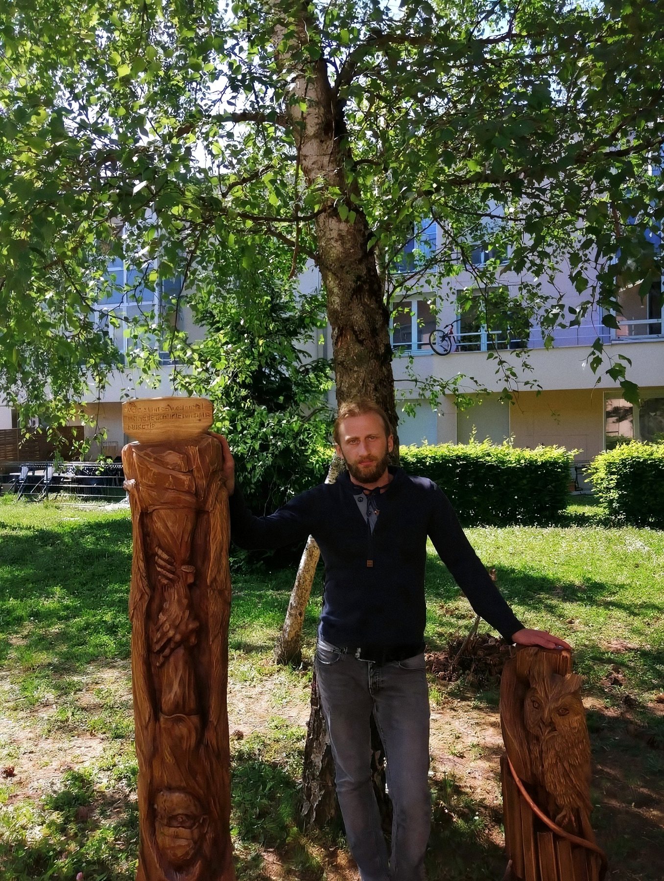 Nika entre deux totems qu'il a sculptés dans le bois, dans un parc