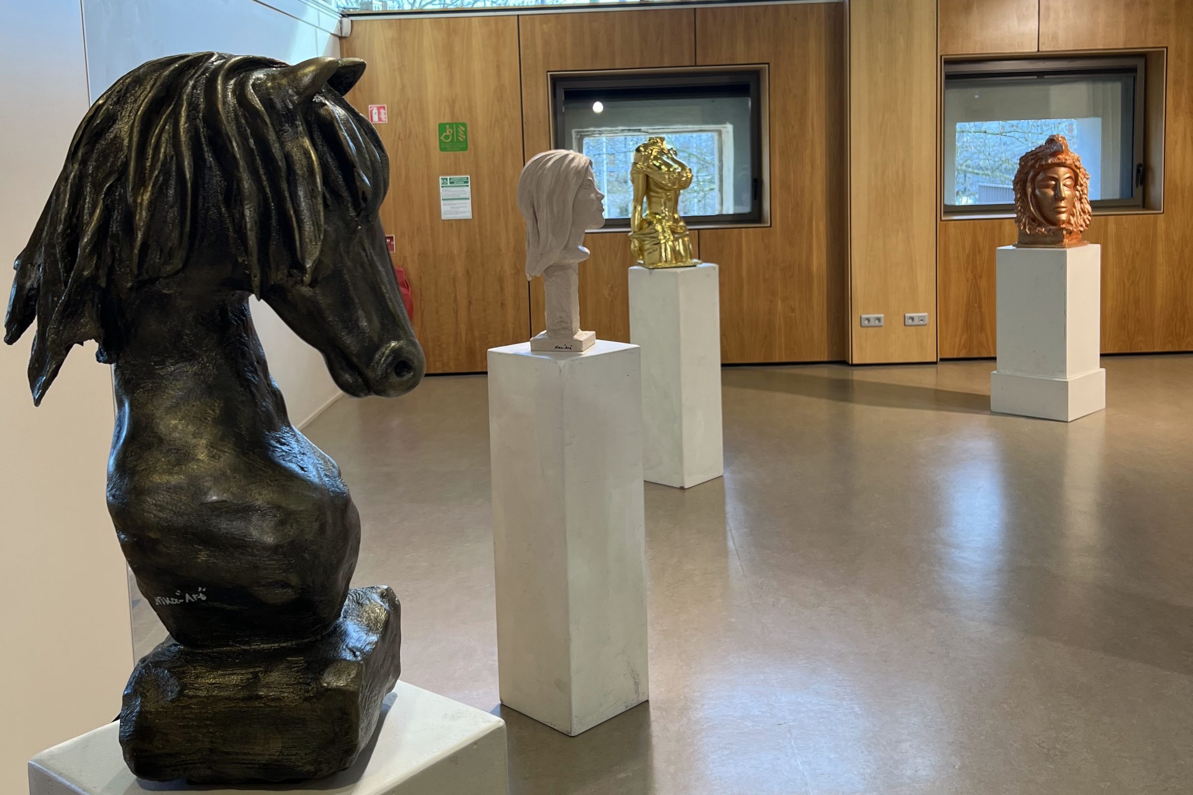 Tête de cheval sculptée au premier plan, salle de l'exposition « Visions libres »