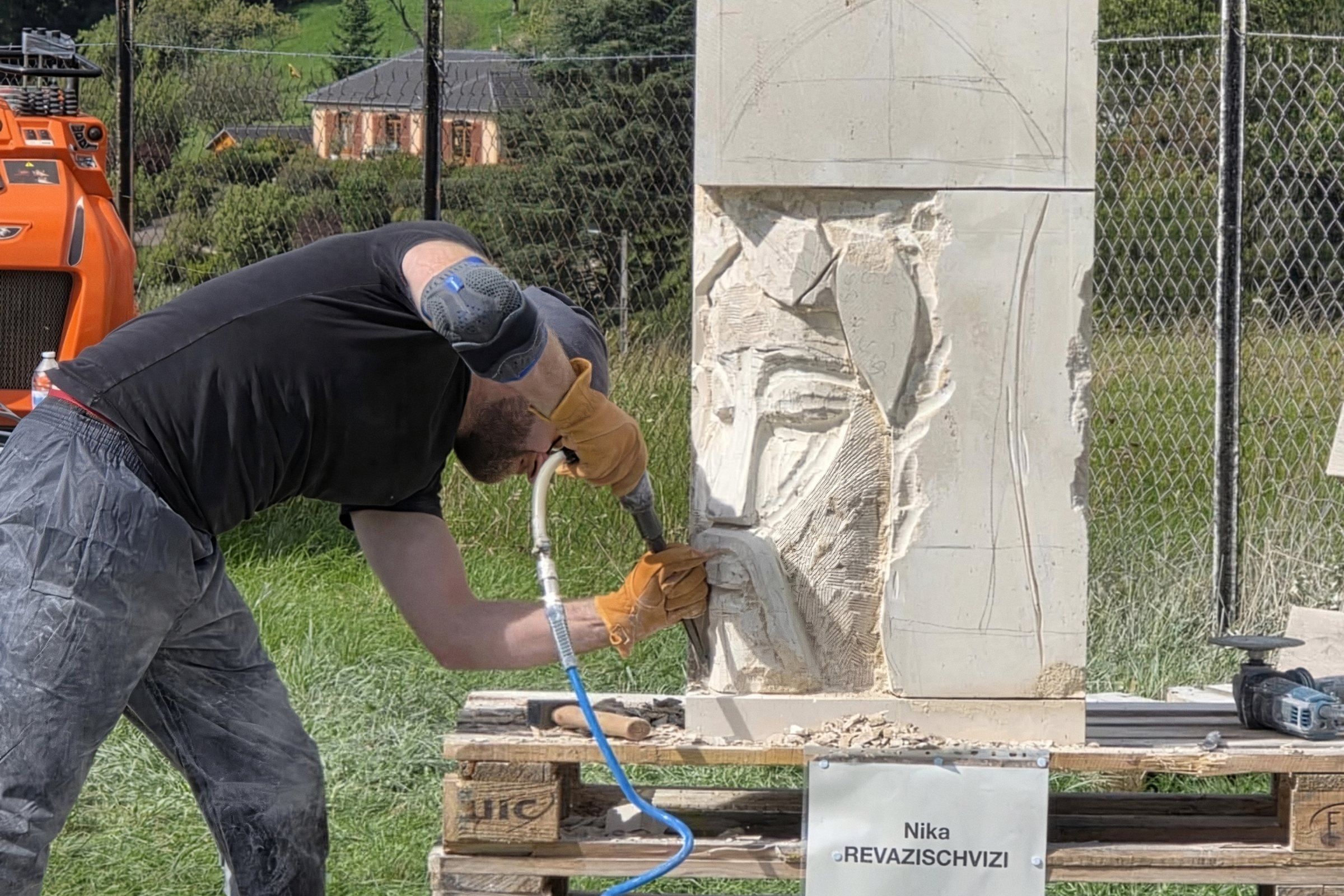 Nika taille une sculpture dans la pierre, à l'atelier de plein air