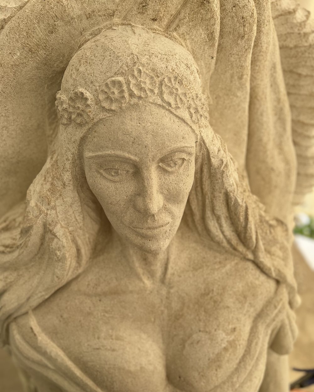 Visage de femme couronné de fleurs, bas-relief en pierre