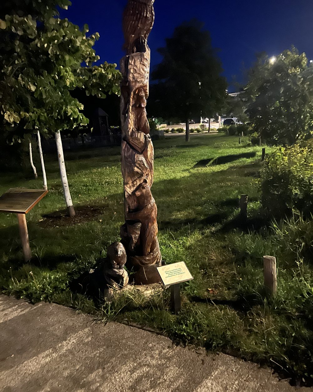 Totem sculpté dans le bois, éclairé de nuit dans un parc