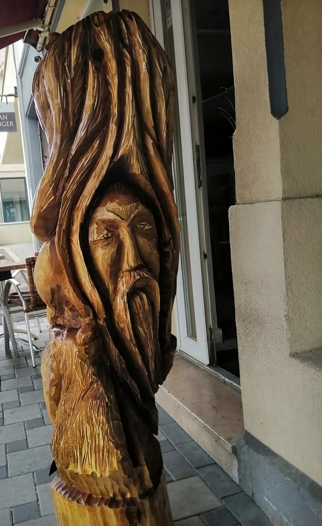 Visage barbu surgissant du bois, sculpture dans un tronc