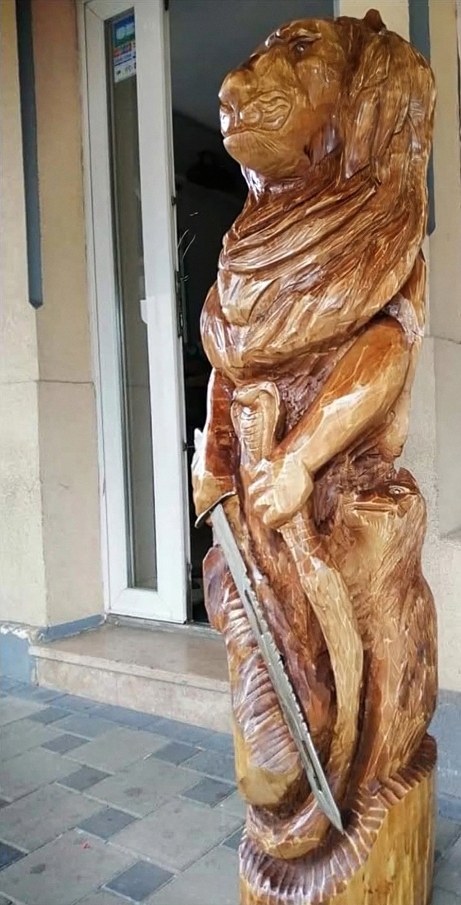 Guerrier à tête de lion tenant une épée, sculpture dans un tronc